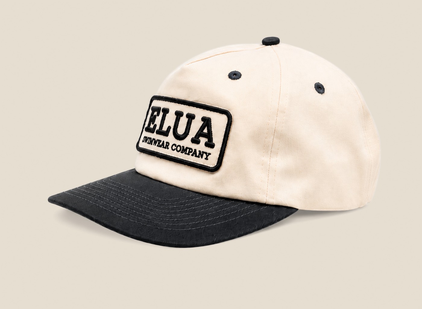 Cream and black Elua Swimwear patch cap, angled view