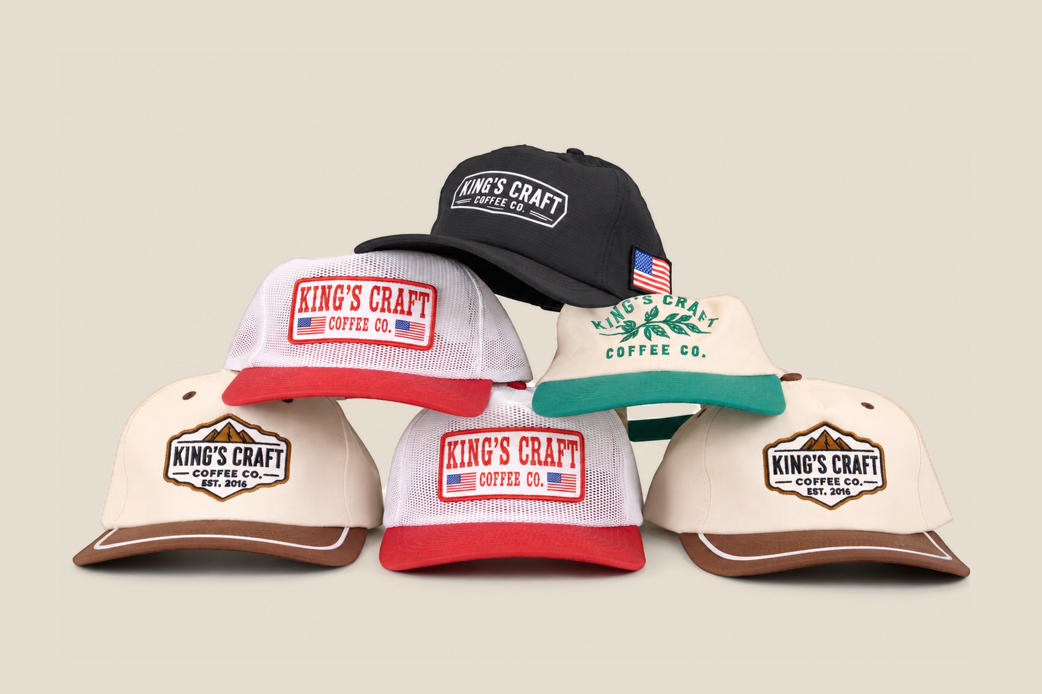 The full King's Craft Coffee run stacked together: cream and green, black ripstop, white mesh trucker, and tan rope caps