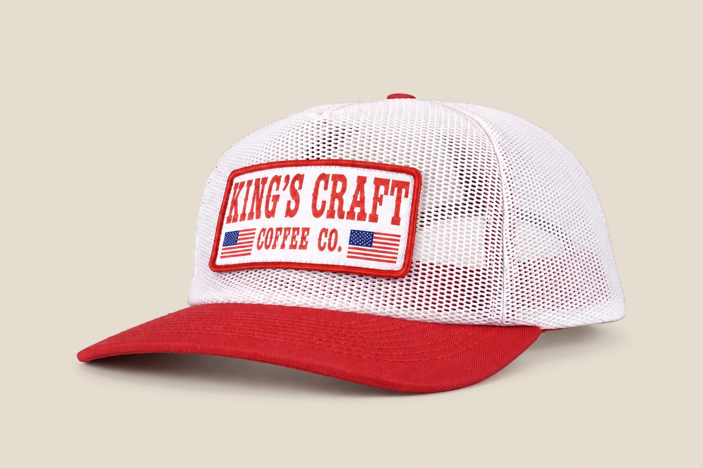 White mesh King's Craft Coffee trucker cap with red brim and flag patch, angled view